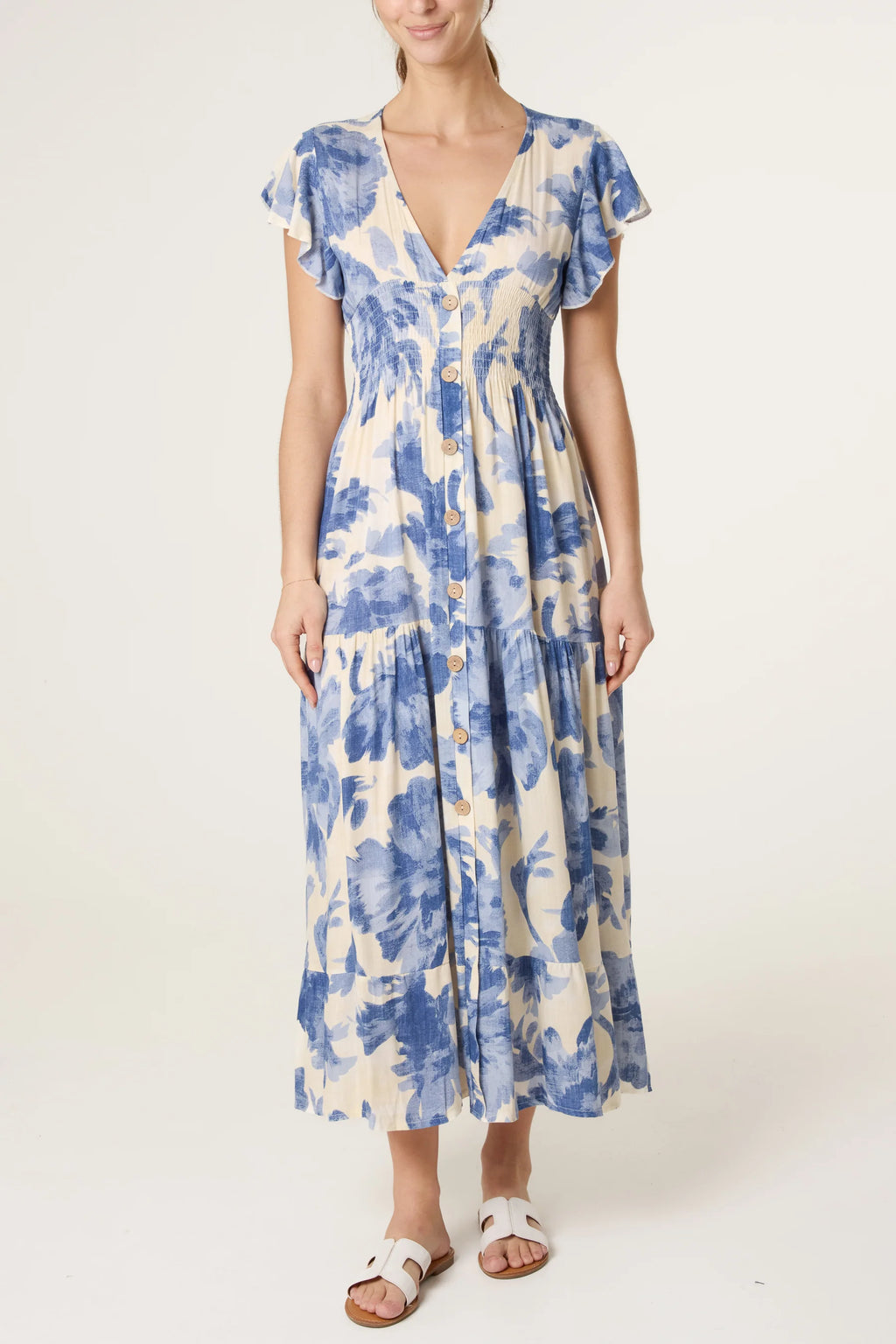 Woman wearing blue and cream floral button-front midi dress with flutter sleeves and V-neck