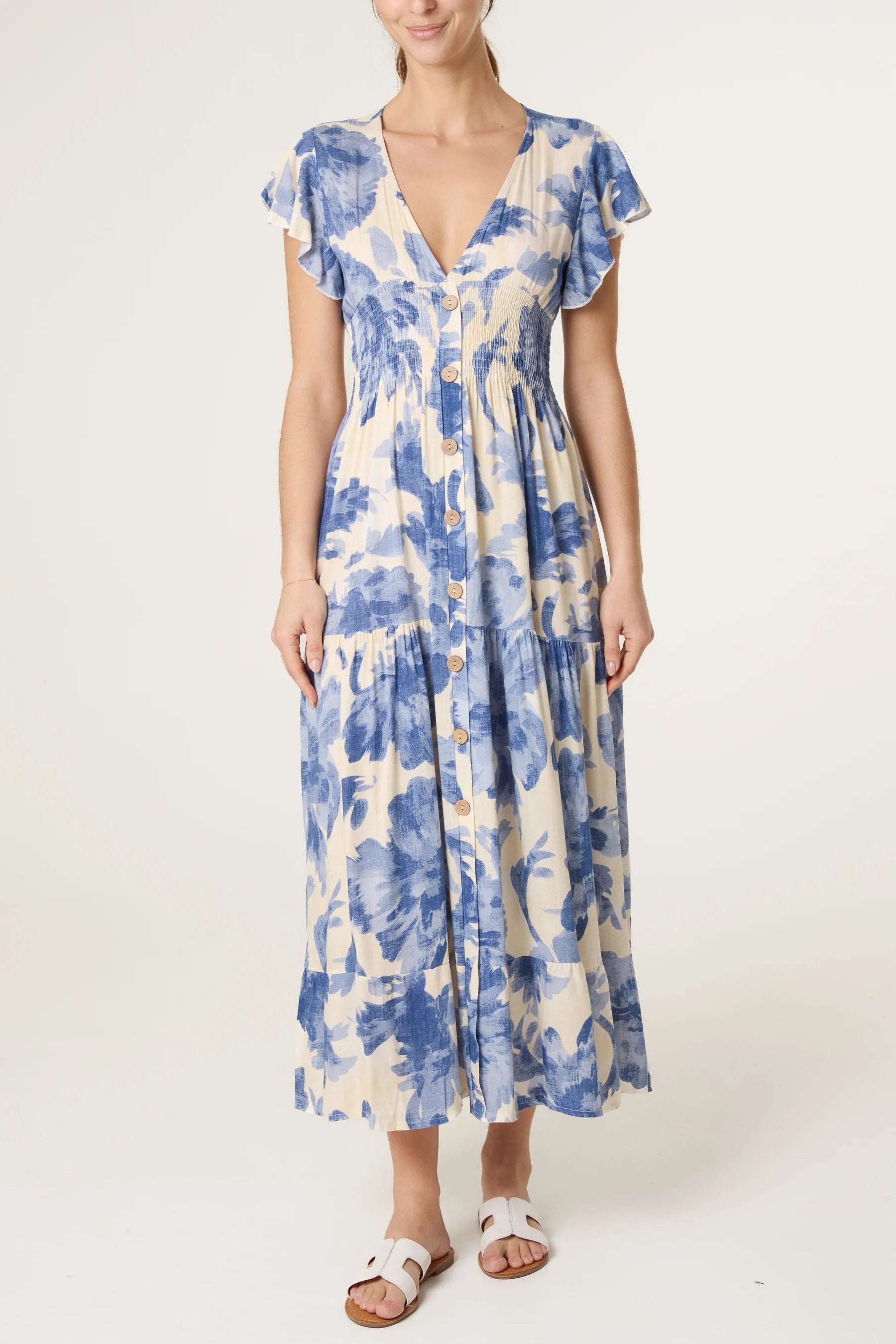 Woman wearing blue and cream floral button-front midi dress with flutter sleeves and V-neck