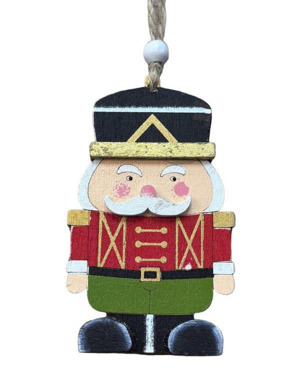 Decorative Christmas ornament shaped like a soldier with a black hat, red coat, and green pants on a white background.